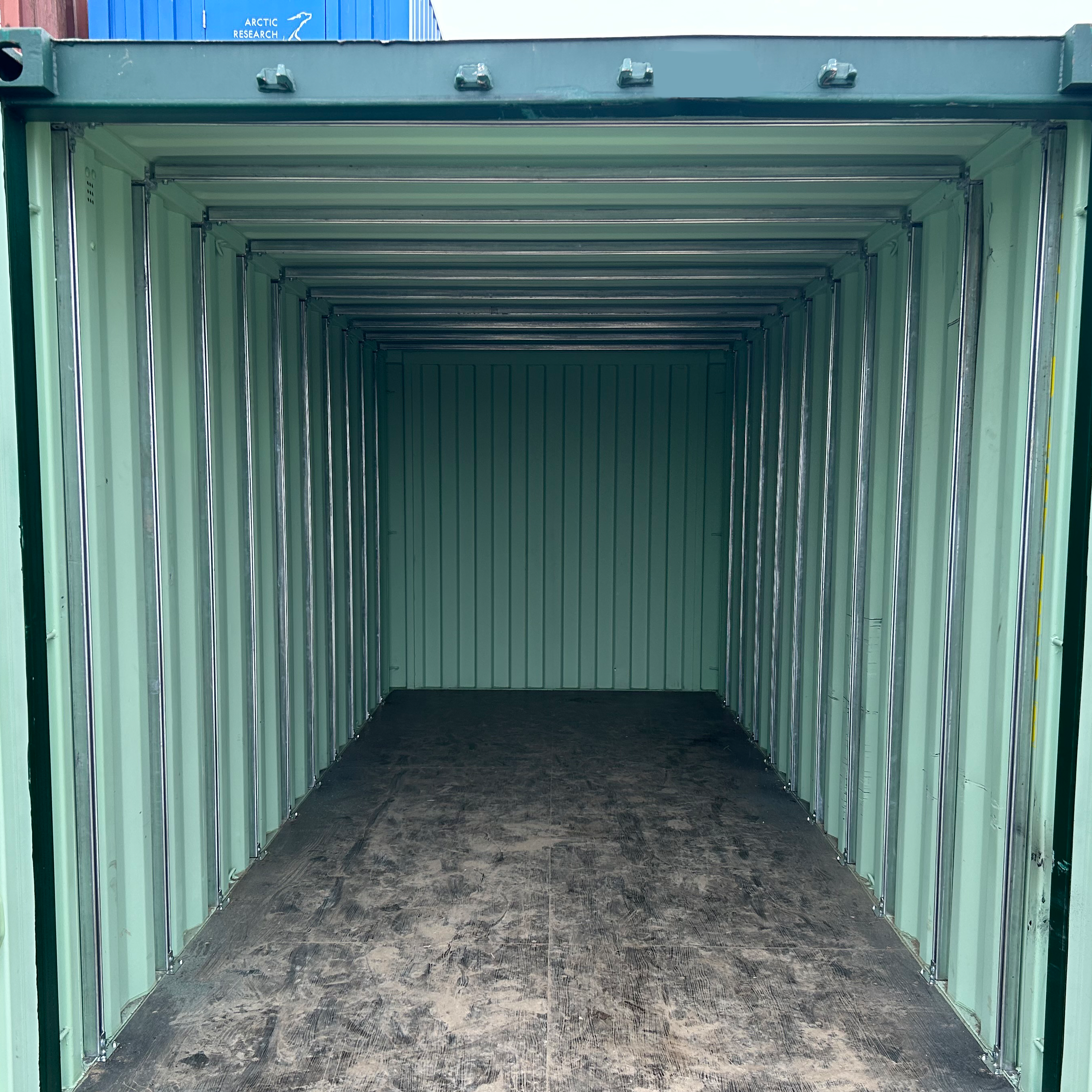 Interior view of a green shipping container fully outfitted with a vertical and horizontal galvanized strut channel framing system, mounted along the walls and ceiling, ready for modular installation or customization.