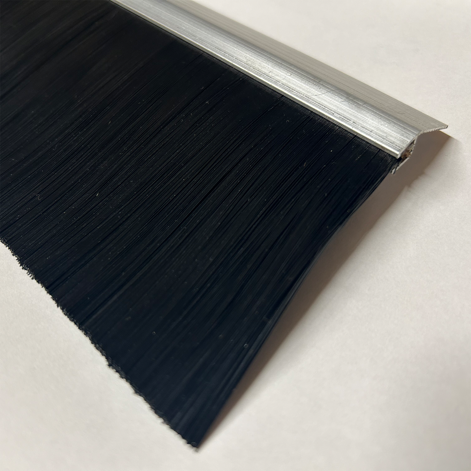 Close-up view of a black brush seal with aluminum holder for roll-up doors, designed for dust and weather protection in container modifications