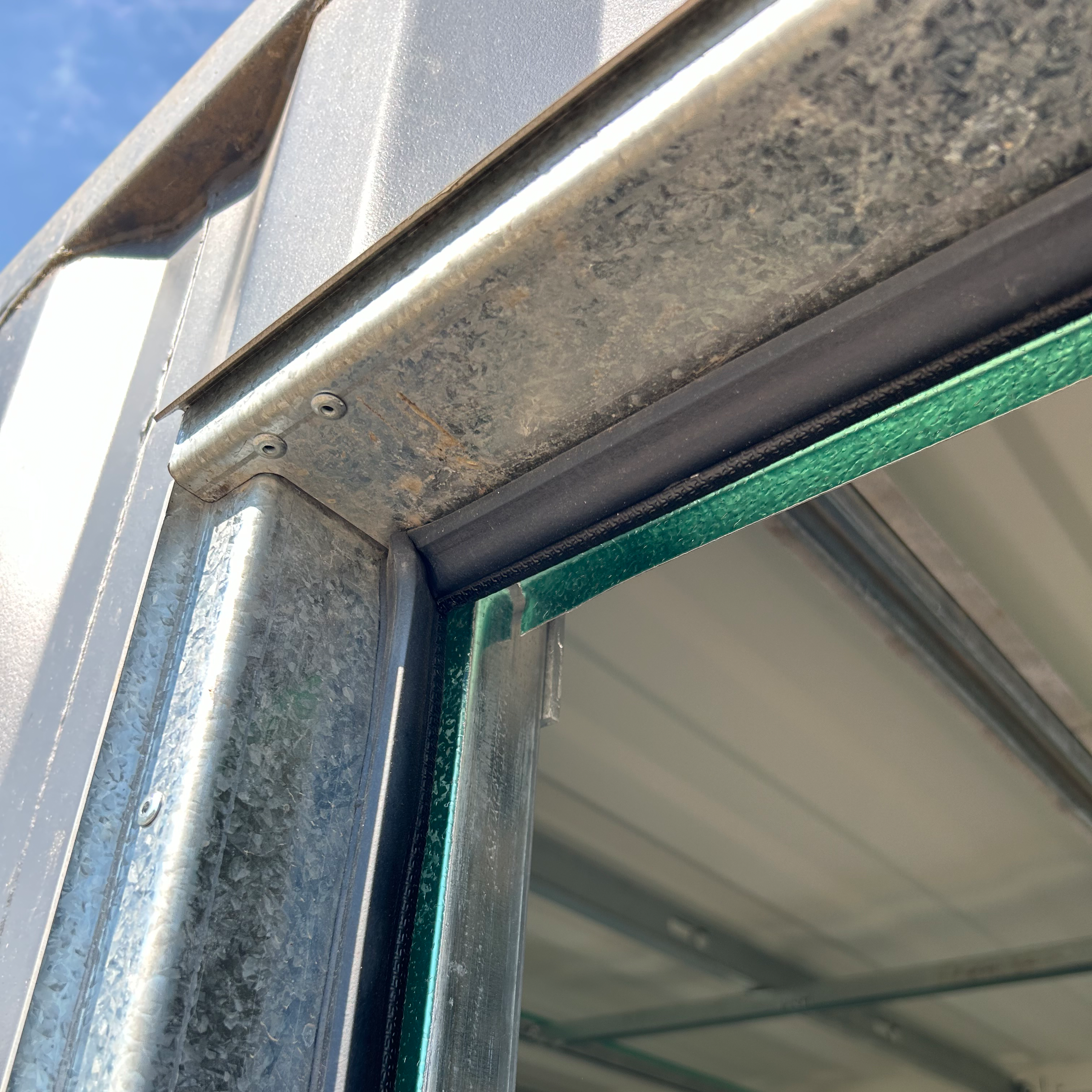 Close-up of fiberglass door slab securely mounted onto the galvanized steel frame, highlighting the hinges, hardware, and weatherproof sealing for shipping container installation.