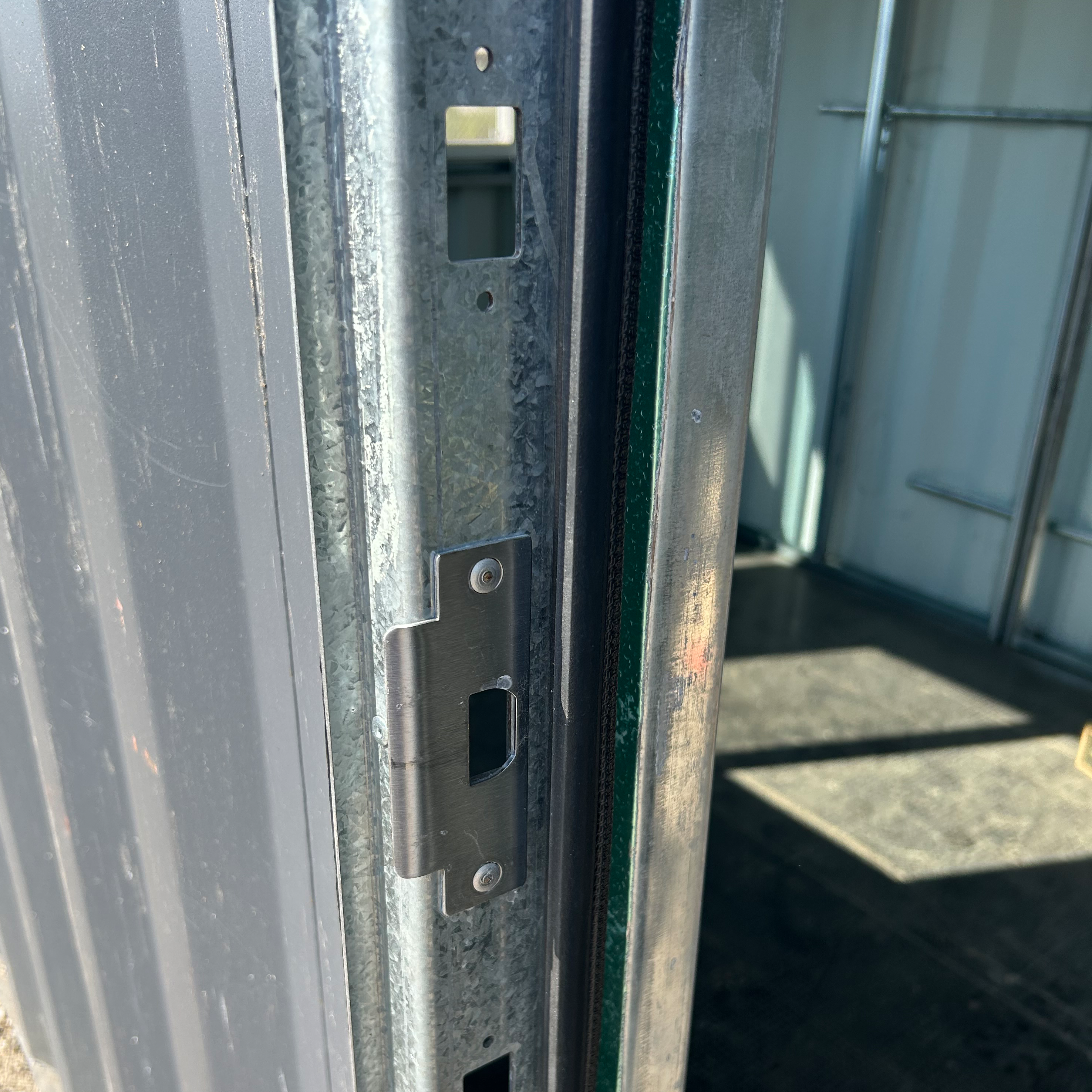 Close-up of fiberglass door slab securely mounted onto the galvanized steel frame, highlighting the hinges, hardware, and weatherproof sealing for shipping container installation.